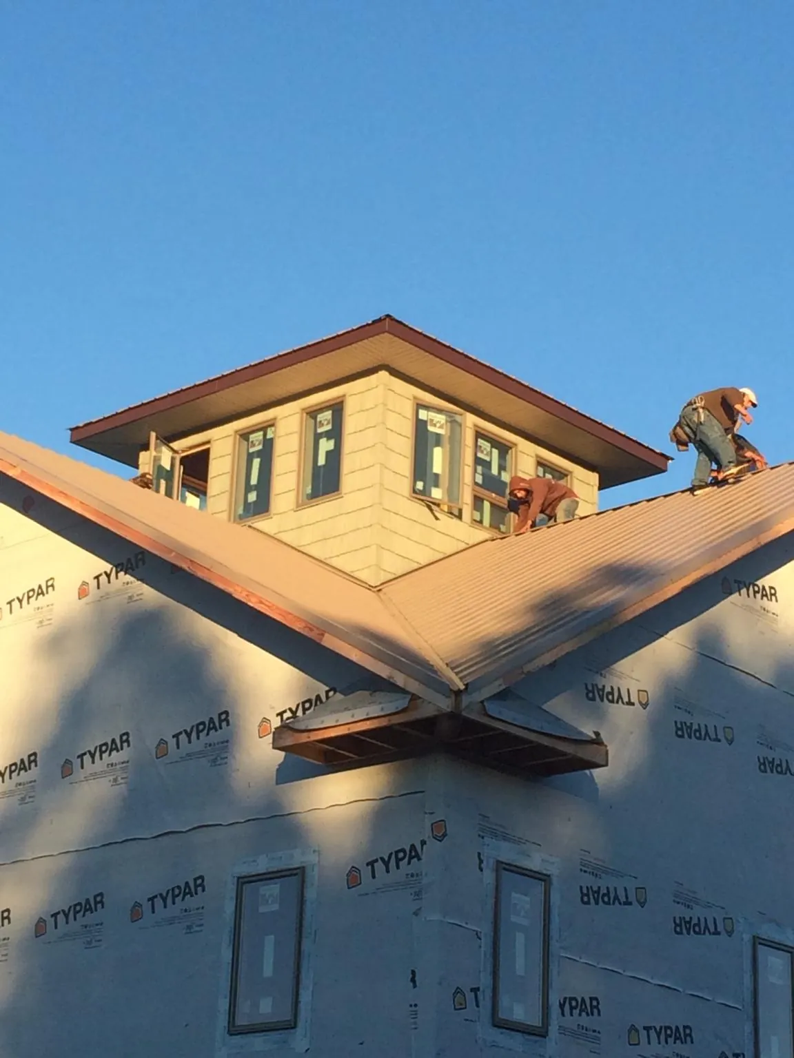 Roofers working around a rooftop cupola on a new metal roof at sunset — Roof Waterproofing in Bridgewater by Roofing Brothers